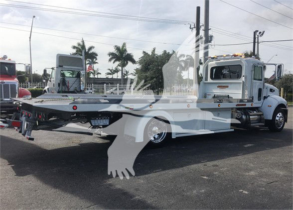 2022 Peterbilt 337 tow truck in a parking lot, side view showing flatbed and rear equipment.