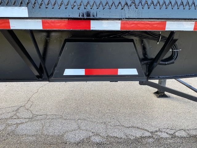 Underbody view of a Transcraft 48 ft trailer showing a central storage compartment with reflective red/white stripe and support frame.