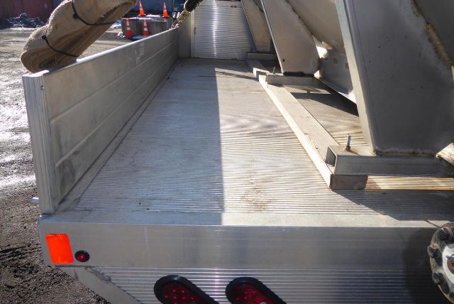 Truck bed of a 2011 Chevrolet 2500HD with aluminum utility bed showing tail lights and ribbed floor.