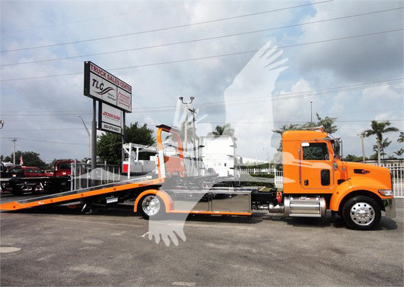 Orange Peterbilt 337 tow truck with flatbed, side view showing cab and long wheelbase.