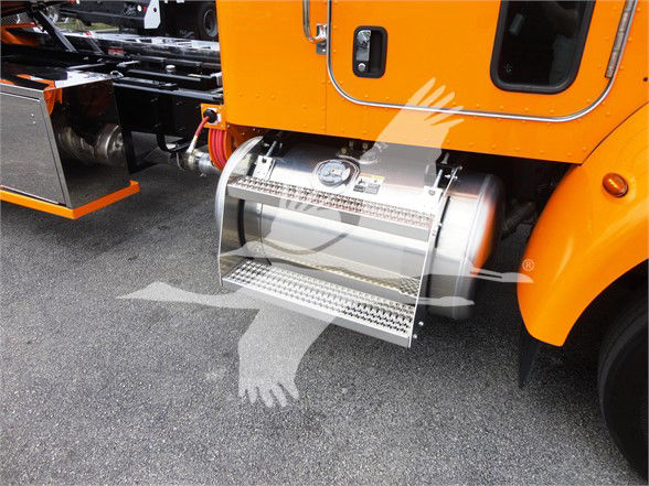 Peterbilt truck side step and fuel tank area with orange cab; diamond-plate step, fuel tank, and door with handle visible.