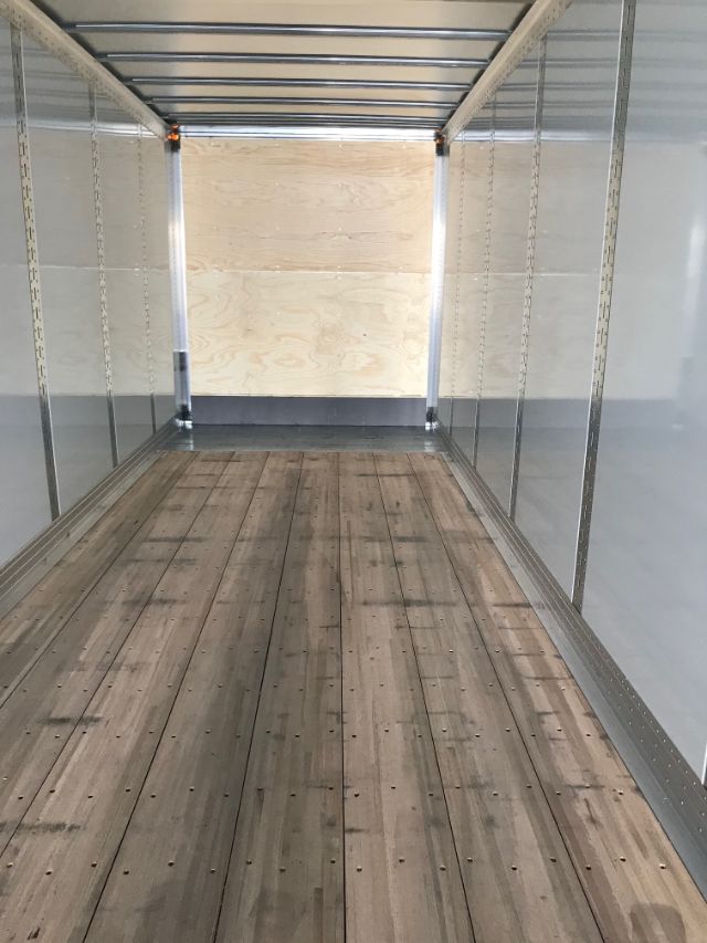 Interior of a new Hyundai composite trailer showing wooden floor, aluminum side rails, and plywood end wall.