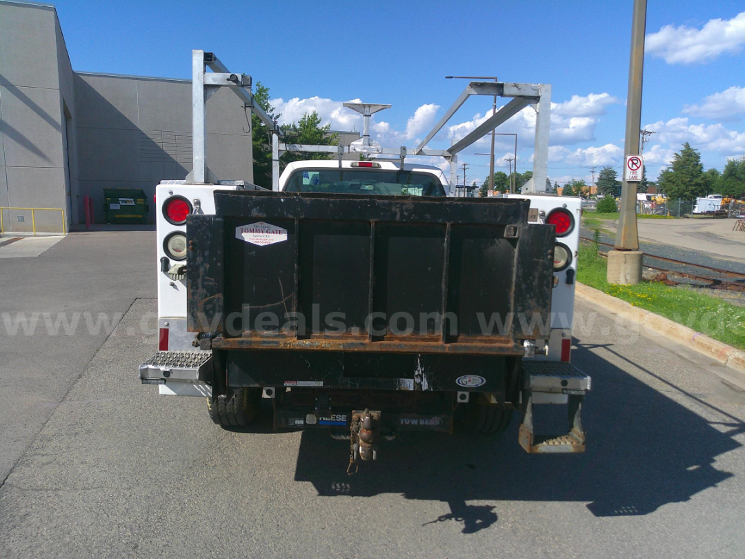 Service/Utility truck rear with black dump bed and towing hitch, seen from behind in a parking lot.