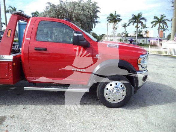 Ram 4500 SLT tow truck side view showing front wheel and 6-lug hub, red cab with black mirrors, chrome steps, and equipment behind cab.