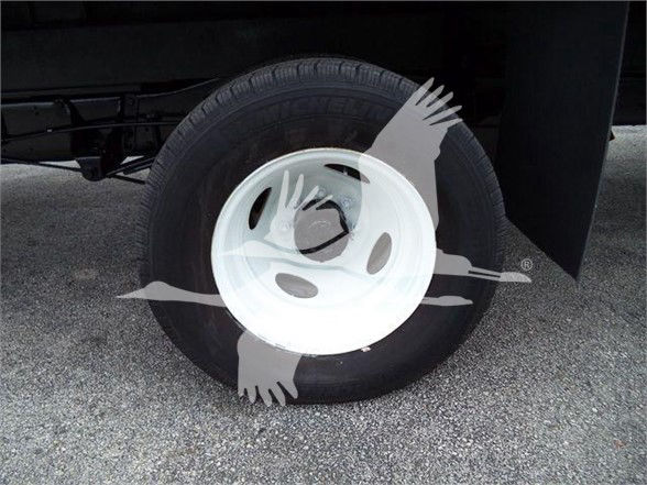 Ford E-450 cargo van wheel with white steel wheel and tire visible. Overlay watermark logo across image.