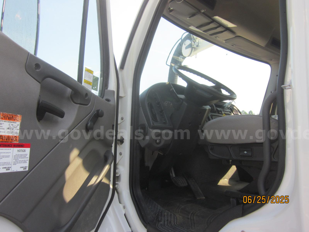 Cab interior of a Freightliner Vactor truck showing steering wheel and dashboard from the driver's door.
