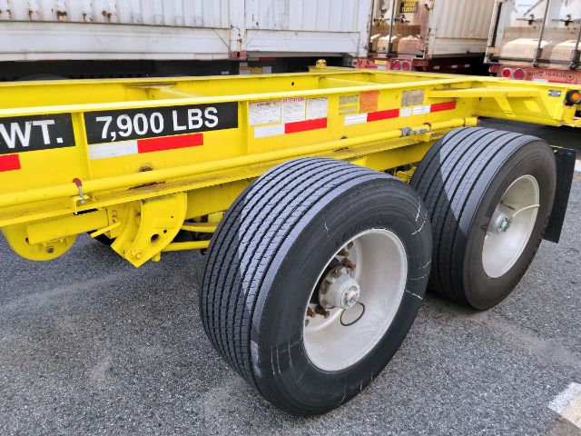 Heavy duty chassis trailer showing dual rear axles with large tires and yellow frame marked Wt 7,900 lbs.