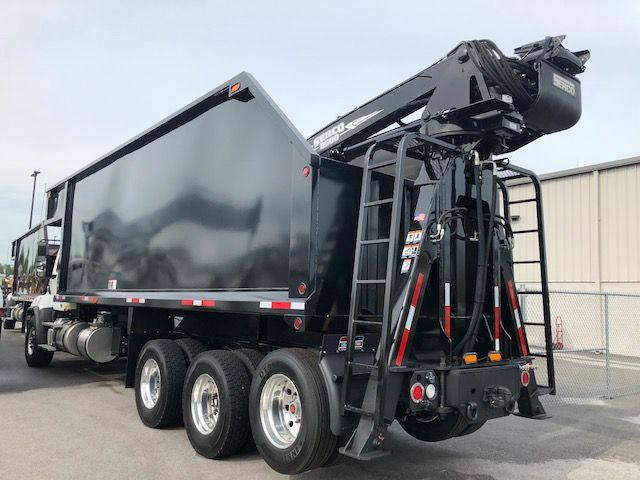 2018 Freightliner 114SD grapple truck with a large dump bed and hydraulic grapple arm on the rear. Side of cab shows Freightliner branding; multiple wheels; no visible text on panels.