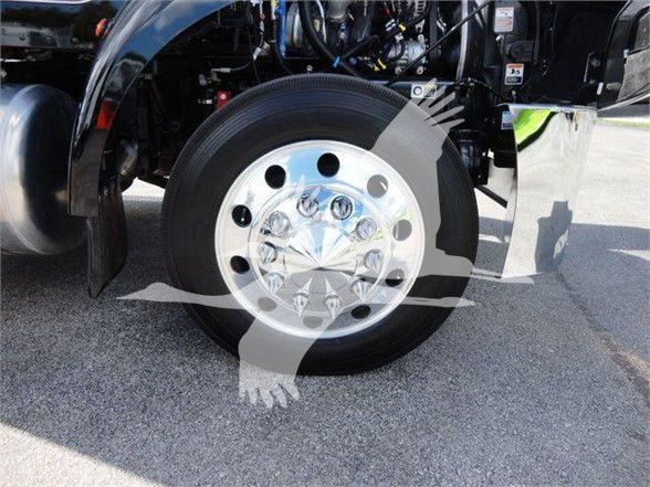 Truck wheel and front dual rear view showing white multi-hole hubcap and black tire in Peterbilt 337 cab area.