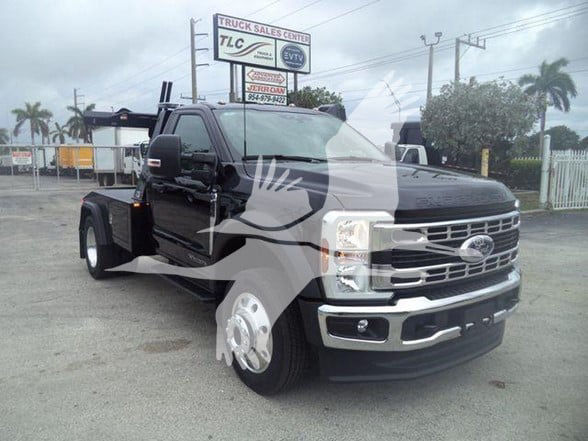 Ford F-450 tow truck front-left view with black body, chrome grille, dual rear wheels, towing equipment mounted at rear, dealership lot in background.