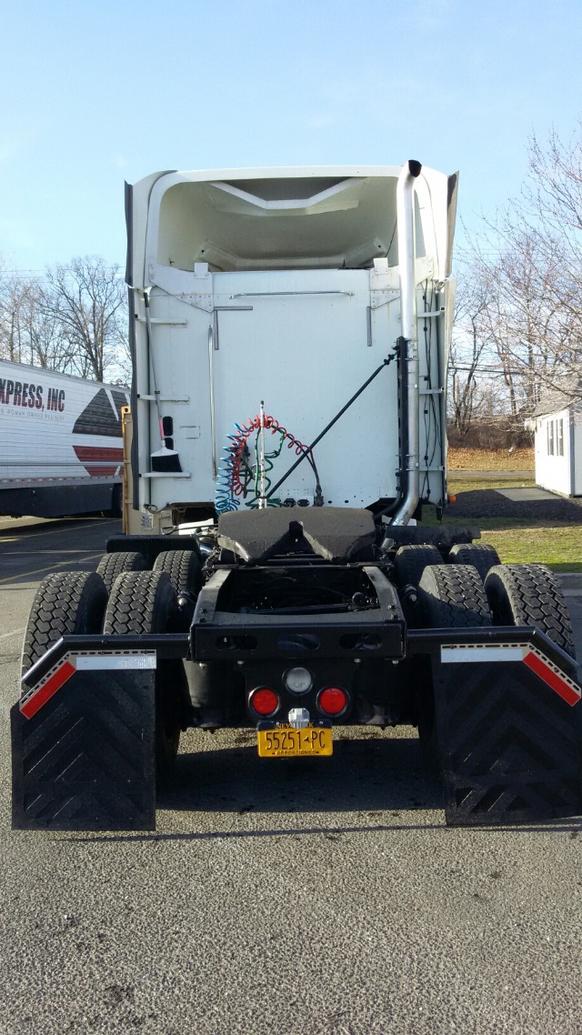 Back view of a 2009 Freightliner Columbia conventional sleeper truck tractor showing rear wheels, fifth wheel, and yellow New York license plate.