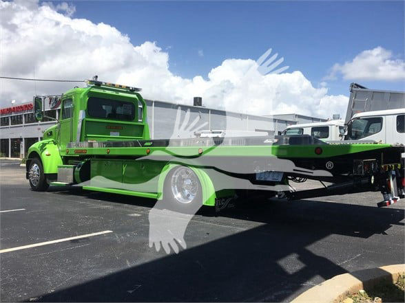 2022 Peterbilt 337 tow truck in bright green color, rear flatbed visible, side view with blue sky and clouds.