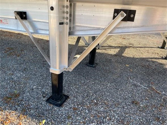 Trailer landing gear and support brackets on aluminum Fontaine REVOLUTION 52 53FT flatbed trailer showing jack legs and frame.