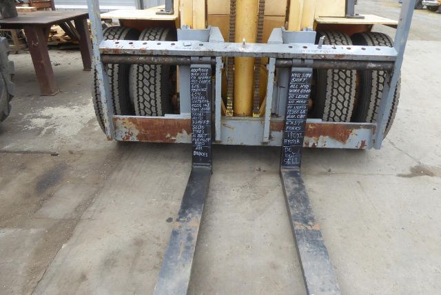 Caterpillar V225 forklift forks and pallet truck frame showing two fork tines with black wear markings and worn metal frame.