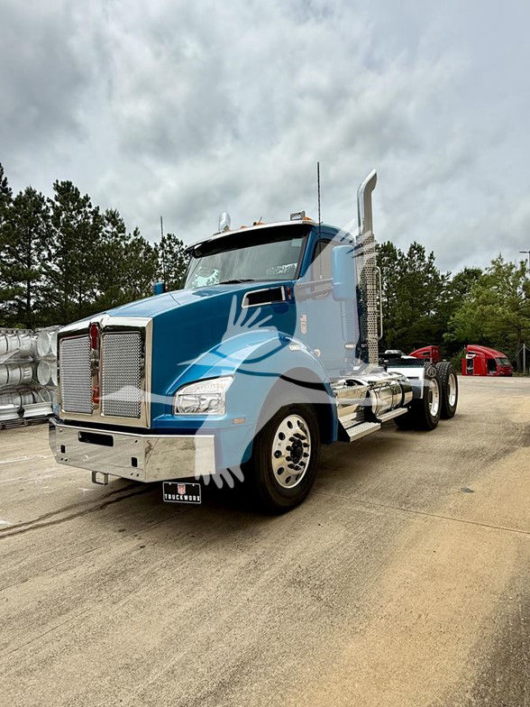 Kenworth T880 daycab truck in blue with chrome grille, dual exhaust stacks, large side mirrors, and polished aluminum steps.