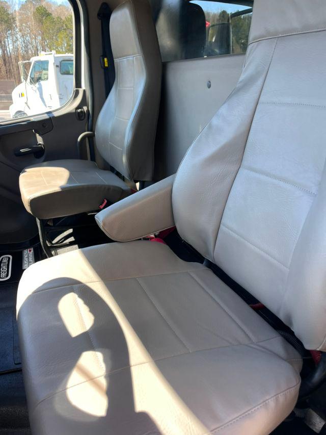 Cab interior of a 2018 Freightliner M2 106 dump truck showing light gray cloth seats in driver and passenger positions.