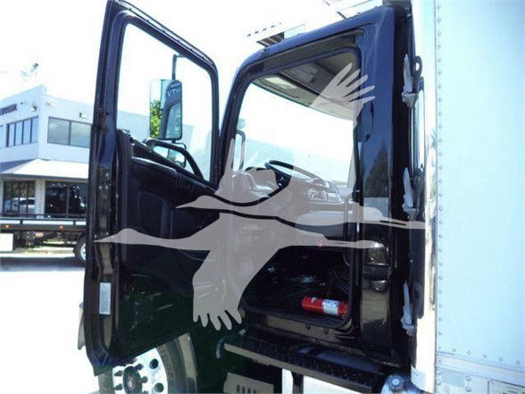 Truck cab door open showing interior dash area with window, seat, and a small fire extinguisher or red object in footwell.