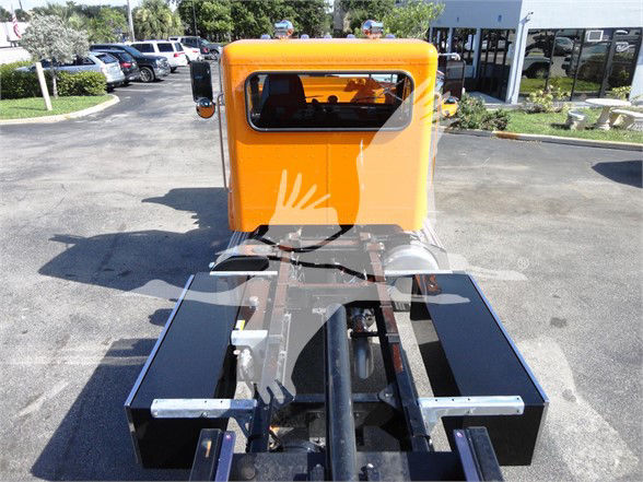 Front cab view of a bright orange Peterbilt 337 tractor with rear frame and attaching hitch visible.
