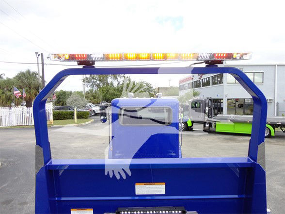  Peterbilt 337 dump bed with blue paint and safety light bar on top, cab rear window, and reflection shows dealership lot.