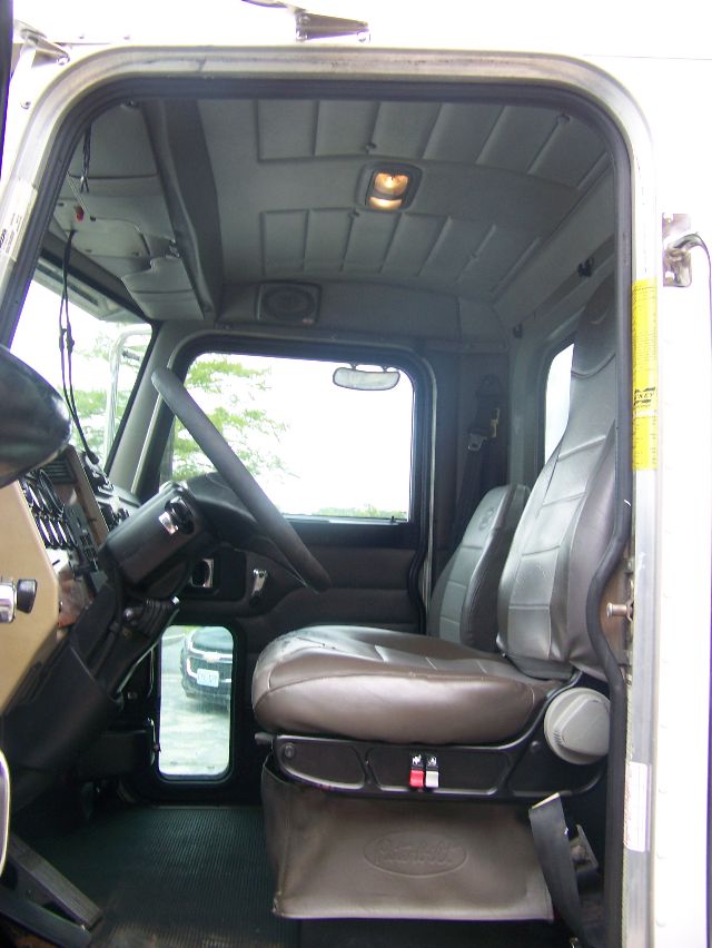 Peterbilt 335 truck cabin interior showing driver seat and steering wheel from open door.