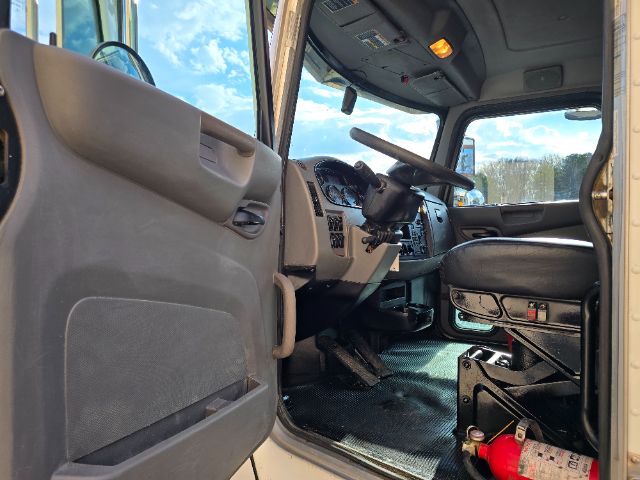 Truck cab interior of a 2017 Peterbilt 348, with dashboard, steering wheel, driver seat, and floor mats visible from the open driver door.