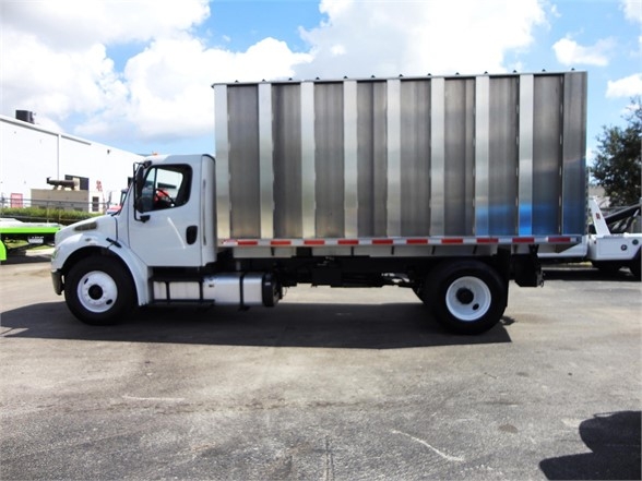 Freightliner BUSINESS CLASS M2 106 chassis with a large silver dump bed, side view showing cab and white wheels.