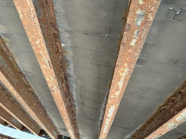 Interior of a Wabash Duraplate trailer showing rusted steel crossbeams and a gray wall panel.