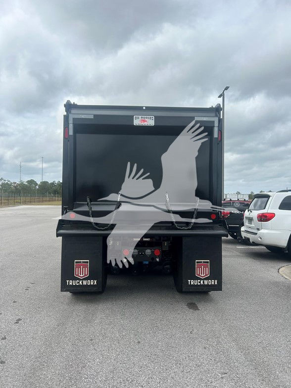 Rear view of a 2026 Kenworth T880 dump truck with a black dump body, dual rear wheels, and TruckWorx mud flaps displaying a red and white logo.