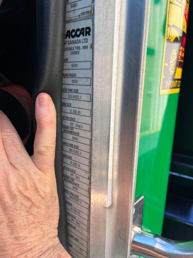Truck door pillar with vehicle tire and sticker, showing wheel and tire specifications near a metal door jamb.
