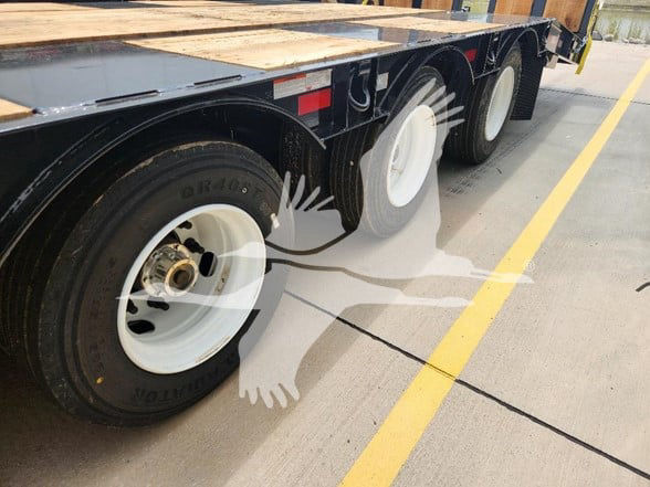 Trailer wheel area showing dual axles with white rims and black tires. Visible text on tire reads 'DR400' and 'VOL…' (partial). No other readable labels visible on components in this view.