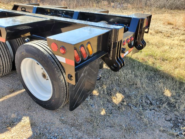 Atoka RG N-553-E lowboy trailer rear corner showing dual rear wheels, mud flaps, and tail assembly with red and amber marker lights.