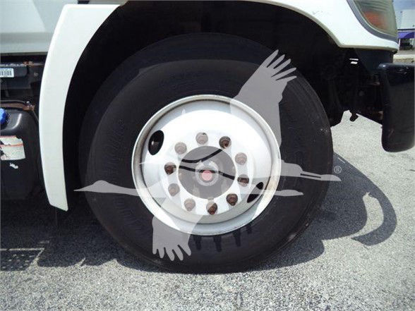 Truck front wheel and fender with white rim, bolted hub, and tire visible; partial cab area seen.