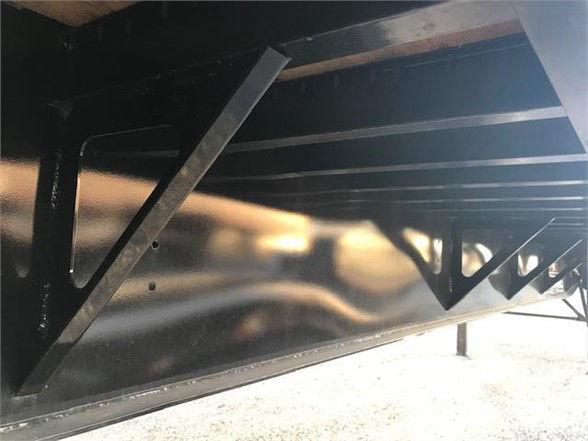 Underbody of a flatbed trailer showing structural framing and support braces with a glossy black finish.