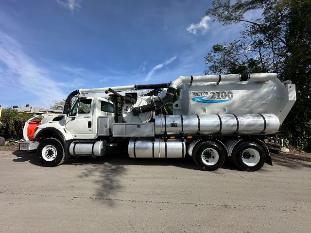 Side view of a 2013 International 7500 vacuum truck with a large white tank and chrome components.