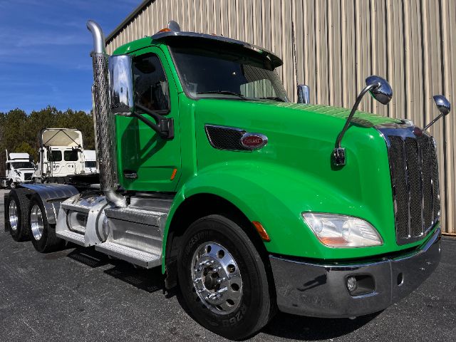Green 2018 Peterbilt 579 daycab truck front view showing chrome exhaust stack and grille