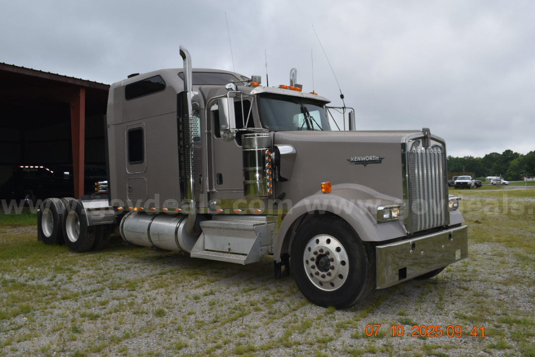 Kenworth W900 cab and chassis truck side view showing chrome exhaust stacks, grey exterior, vertical grille, and Kenworth emblem on the hood.