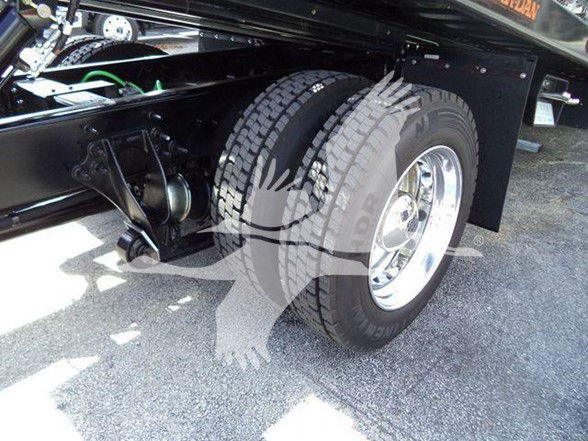 Tow truck rear wheel area showing dual rear tires, chrome rims, and part of suspension undercarriage.