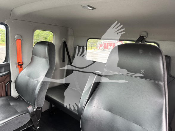 Cab interior of a 2026 Hino L6 truck showing three seating rows with black leather seats and orange seatbelt on left side. No visible dashboard text.