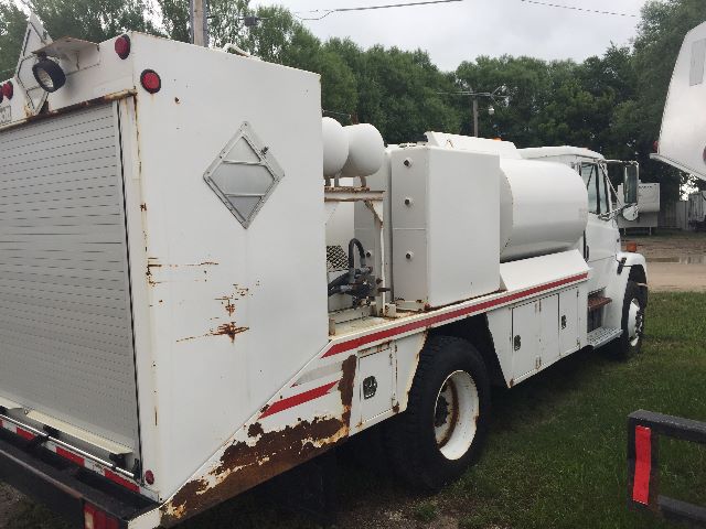 Freightliner FL-70 street side of a service truck with large white cylindrical tank and compartments.