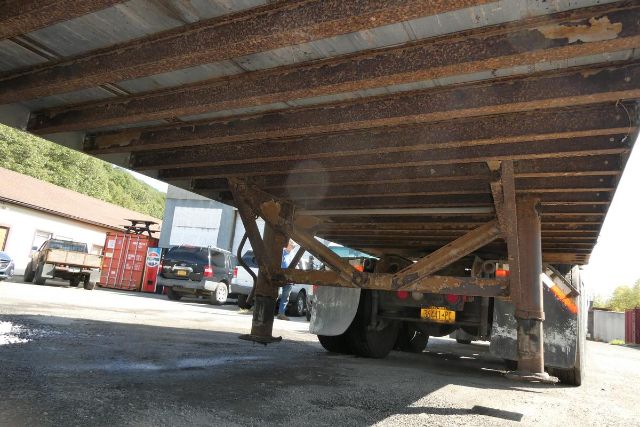 Trailer underside showing Fruehauf FB9T248 with support beams and wheels visible underframe and license plate area.