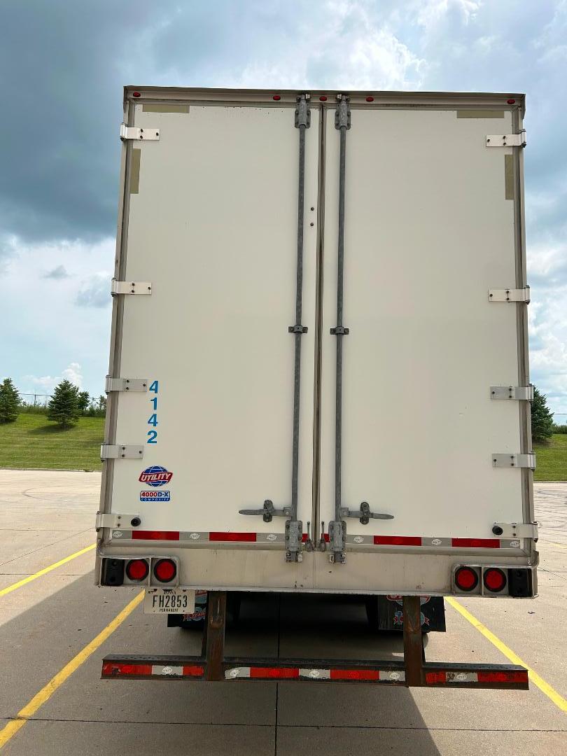 Rear view of a white 2020 Kenworth T680 dry van trailer with double barn doors, blue serial numbers on left door, Utility brand sticker, and license plate FH2853.