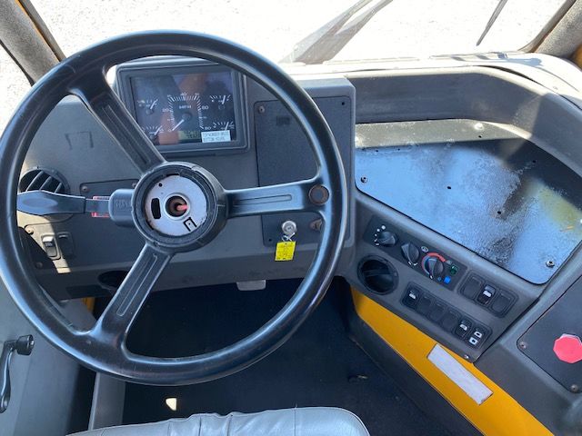 Truck cab interior with large steering wheel, dashboard gauges, and control panel. Visible labels: none clearly legible.