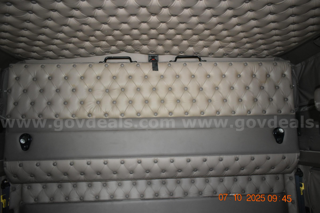 Cab interior with tufted beige upholstery and diamond stitching, storage headboard, and mounted latches.