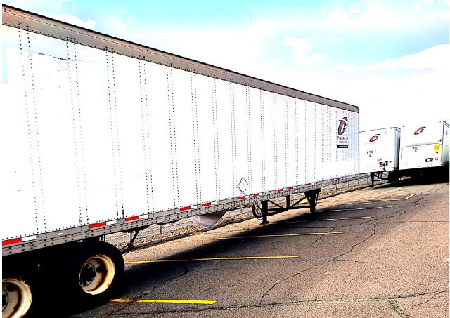 Trailer side of a 2005 Wabash roll-off trailer showing white corrugated side panels, wheels, and landing gear; visible logos near rear.