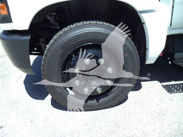 Front wheel of a Chevrolet Silverado 6500HD in a showroom or lot, with tire and wheel assembly visible.