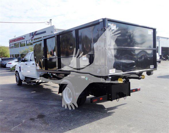 Truck bed with large black refuse body mounted on white Chevrolet Silverado 5500HD chassis, rear view showing hitch and safety lights.