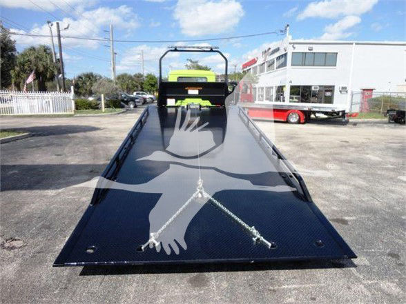 Flatbed tow truck platform with two steel tie-down chains and center access rail, viewed from front, Mack MD6 listing.