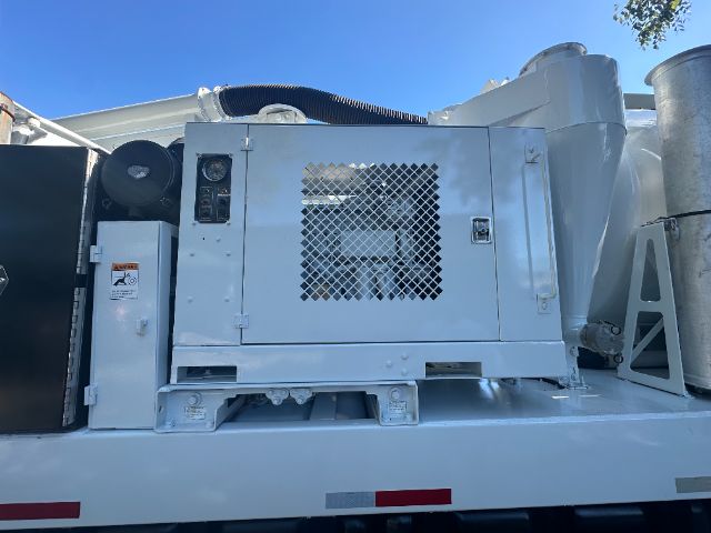 Industrial generator or engine compartment on a white truck chassis, with a vented panel and control box.