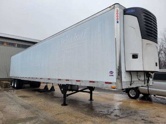 Trailer in side view showing Carrier refrigeration unit and Thermo King style trailer with mud flaps and landing gear.