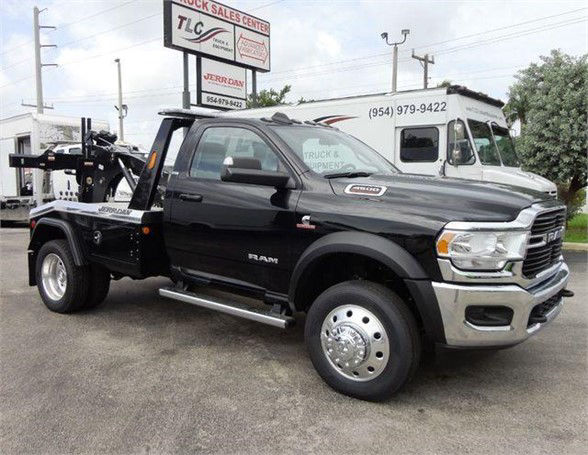 Ram 4500 tow truck in black with chrome front, flatbed equipment in rear, dealership lot in background.